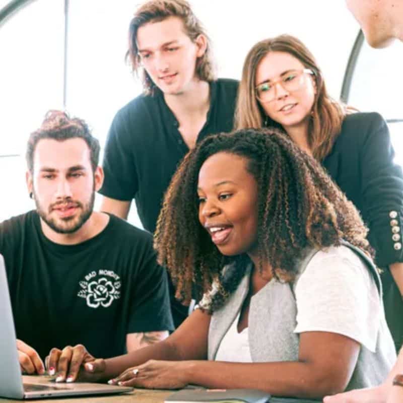 a group of people around a laptop