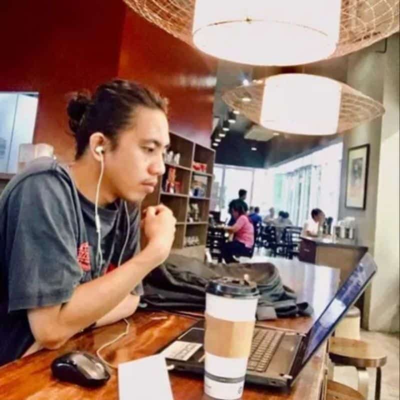 a man sitting at a table with a laptop and a cup of coffee